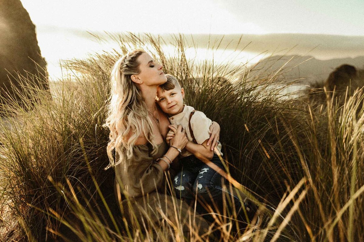 Oregon-Coast-tall-grass-session-Stormy-Solis-Hometown-retreat-mother-holding-her-son-in-Kara-Thomps-dress