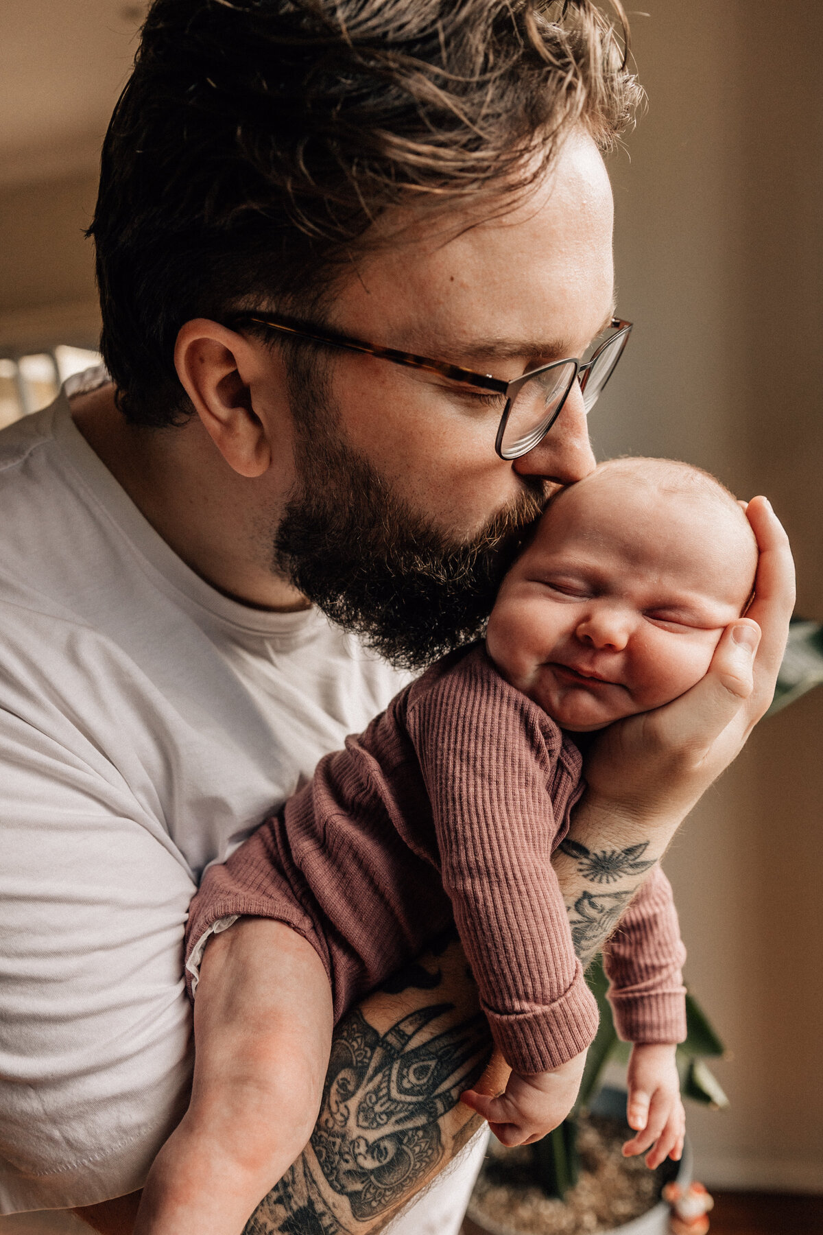 Dad holds newborn baby in arms and kisses on head