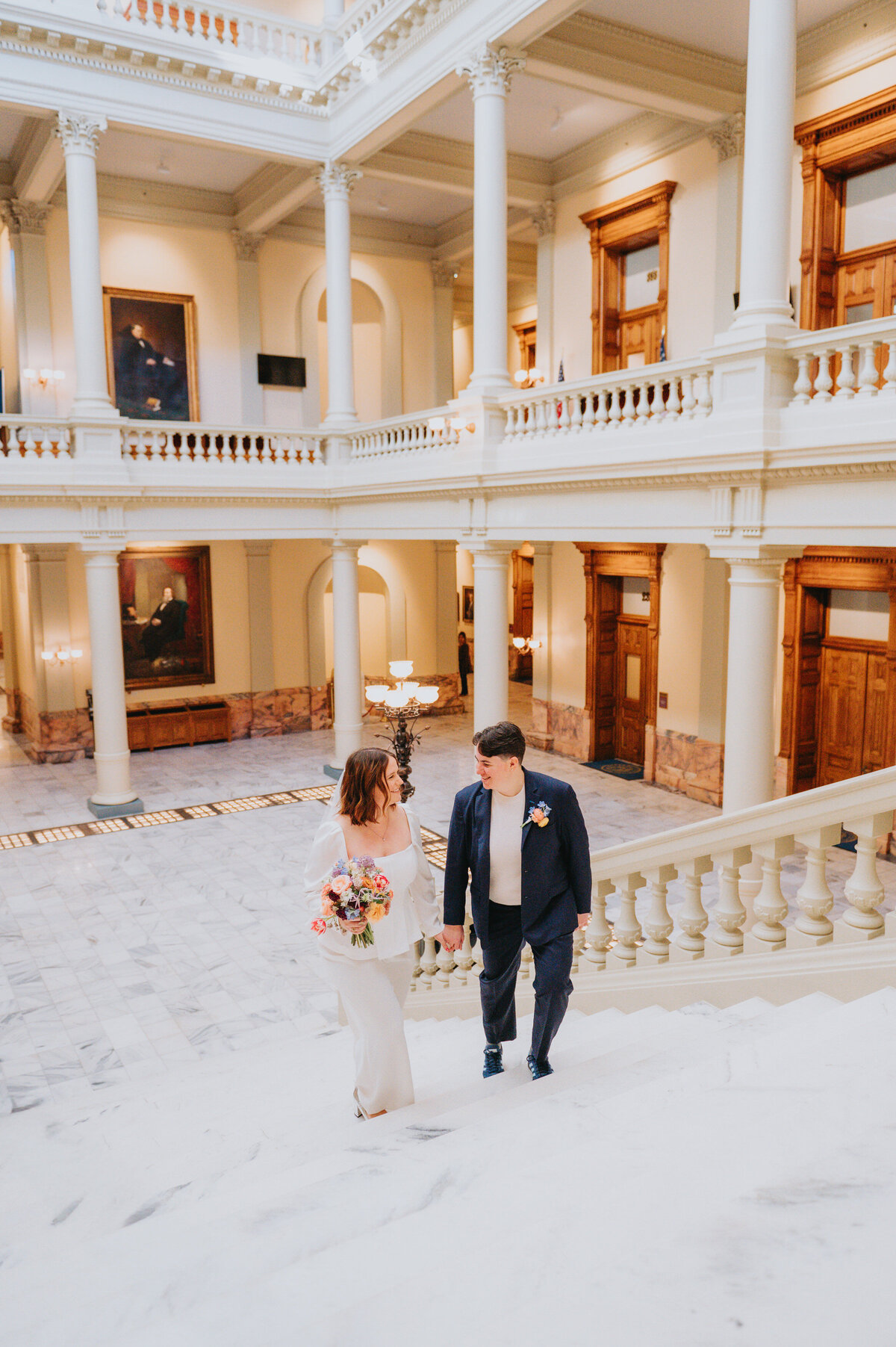 Newlyweds walk up white steps in a courthouse