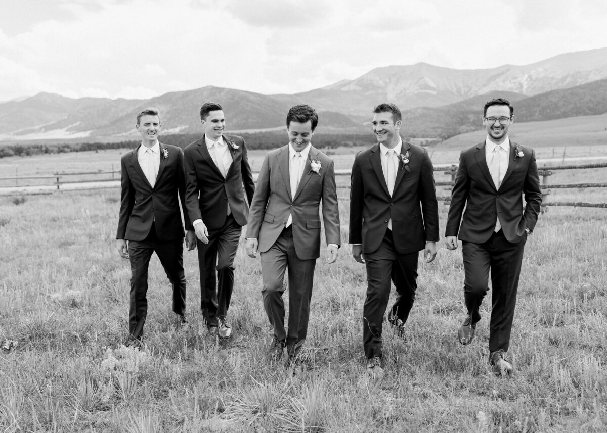 Groom and his groomsmen laugh and walk together before the wedding ceremony