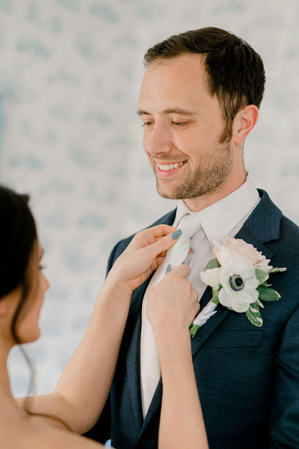bride fixing grooms tie for getting ready photos together