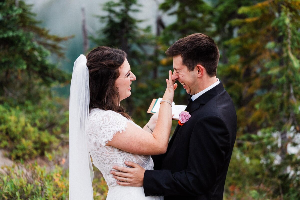 bride wiping tears from groom's eyes during vow reading at a Washington alpine lake.