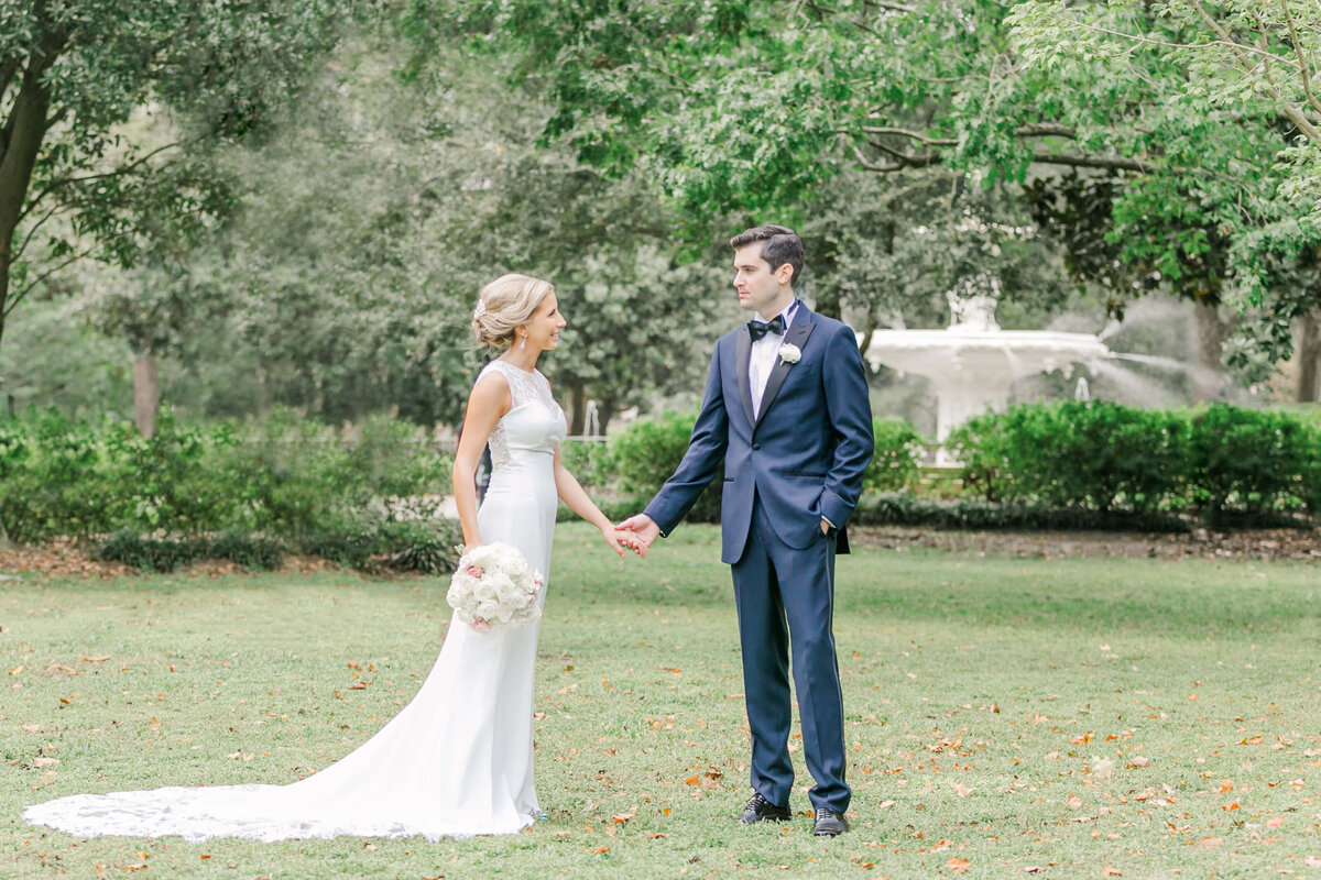 A bride and groom hold hands in a garden lawn chatting