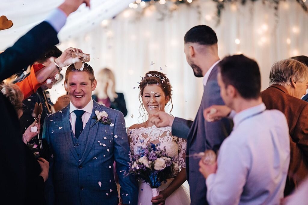 A bride and groom walking down the aisle with confetti being thrown at them