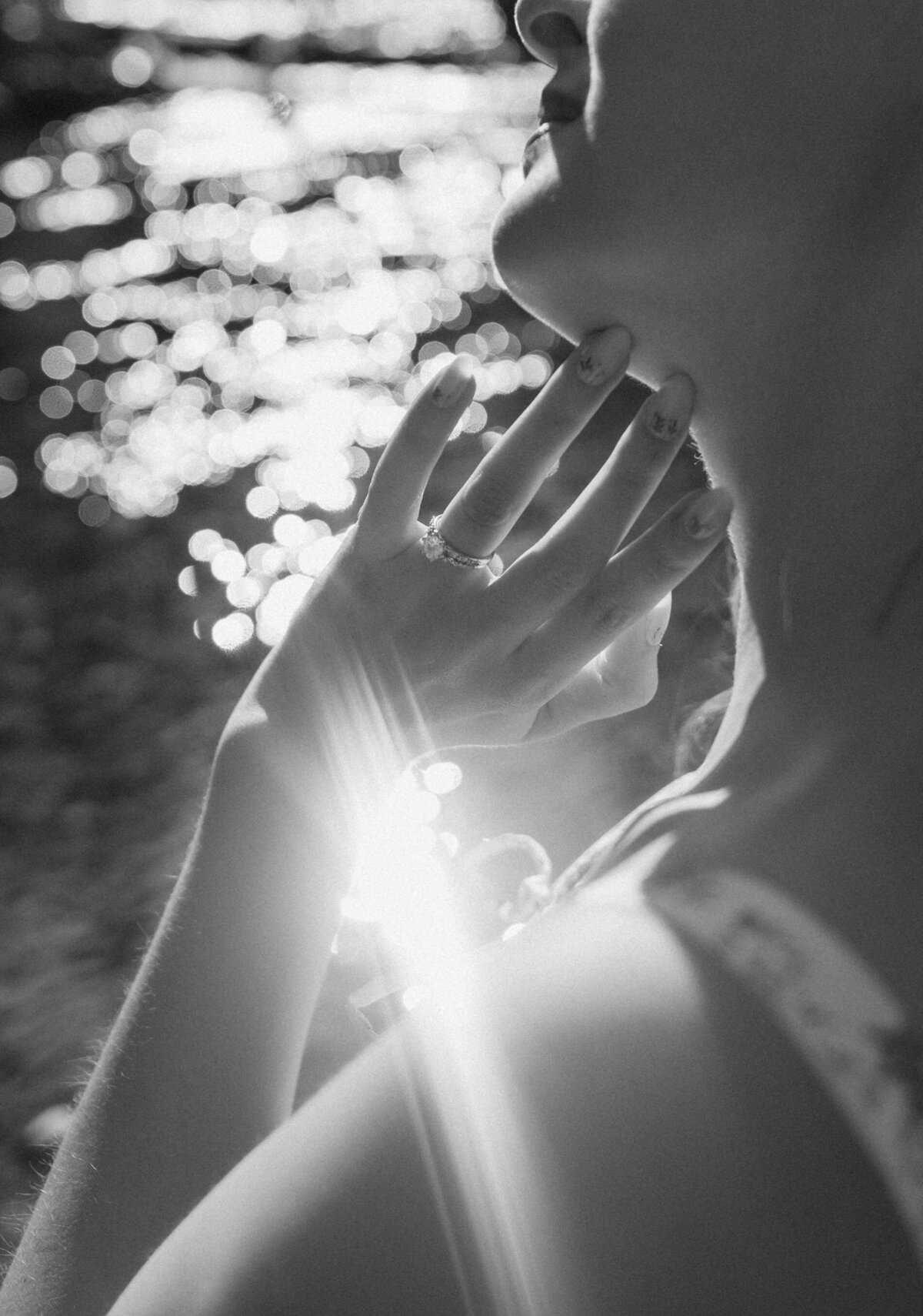 woman gently touches her face while sitting in the golden sun near the river in Bend, Oregon