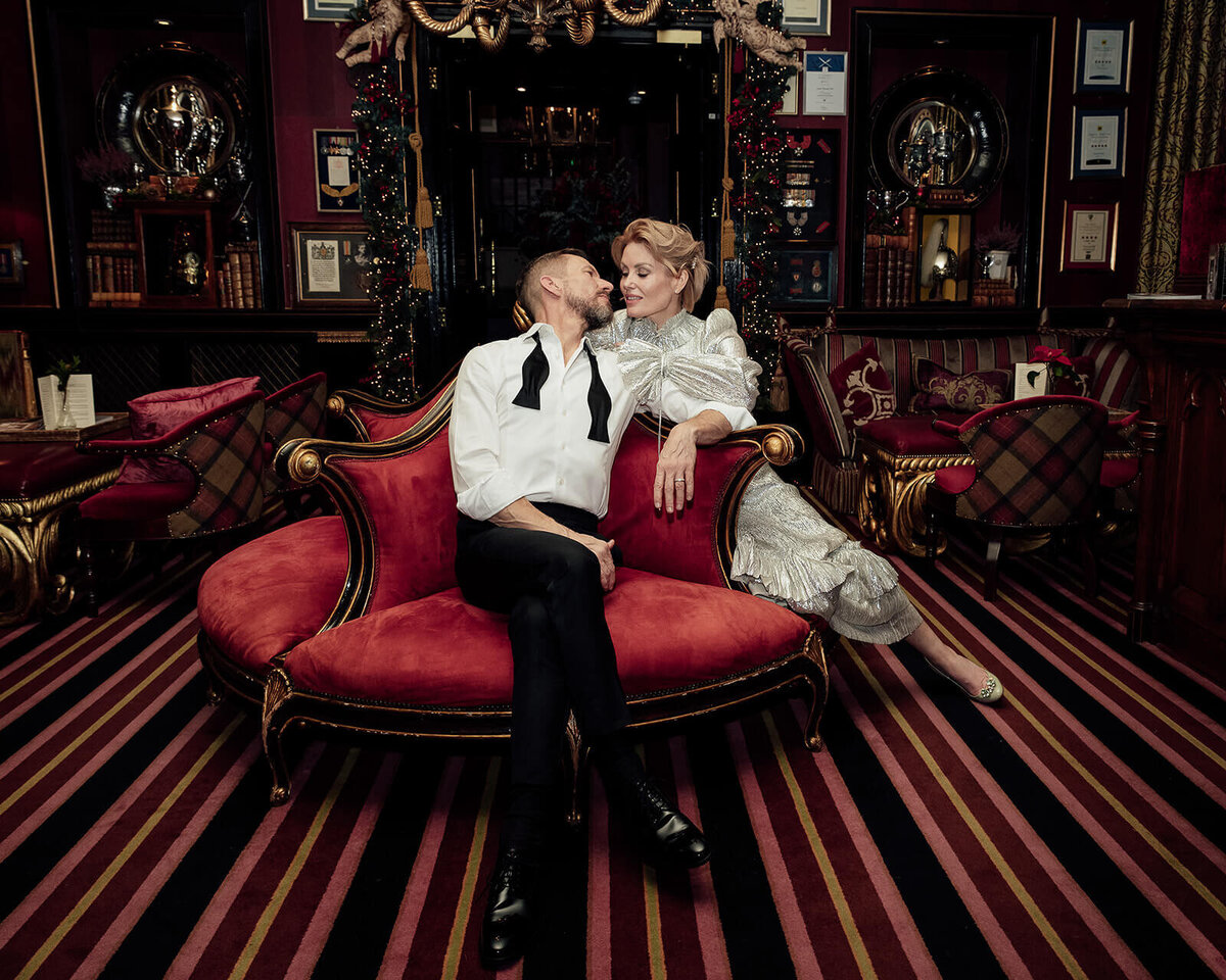 Bride and Groom sat deeply love in a red chair at Prestonfield House. 