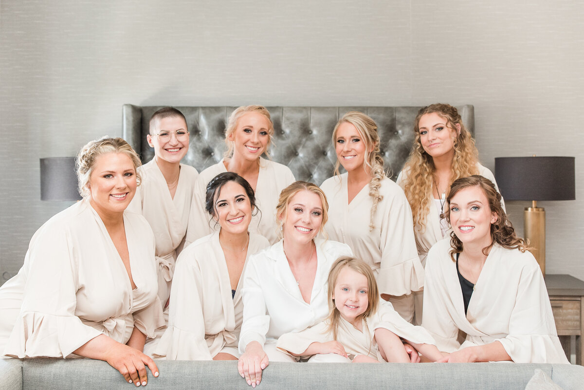 bride and bridesmaids smiling in bed champagne robes