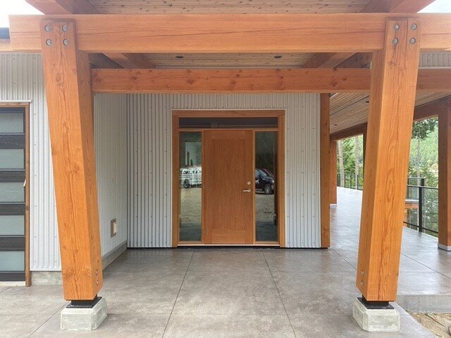 Timber frame home entry with wood beams and entry door with sidelights.