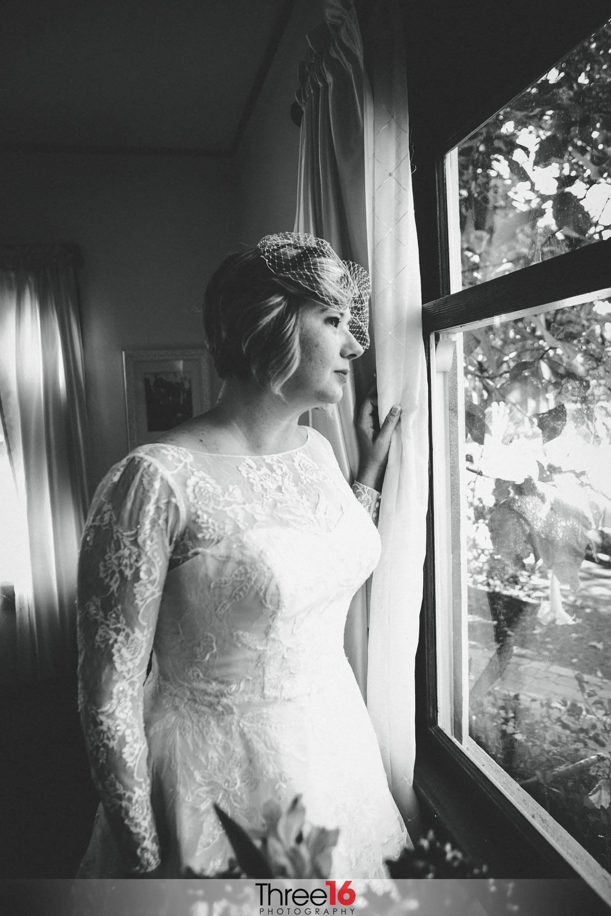 Black & White photo of Bride looking out the window prior the her wedding ceremony