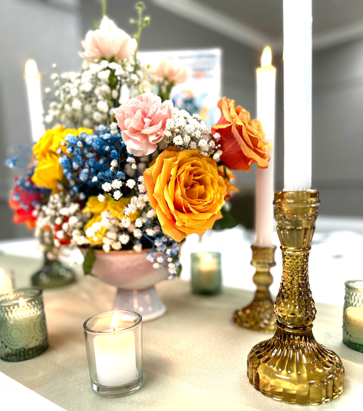 Vibrant floral centerpiece featuring bold, colorful blooms, elegantly paired with gold and glass candle holders for a sophisticated tablescape, designed by In Full Bloom Event Planning & Design