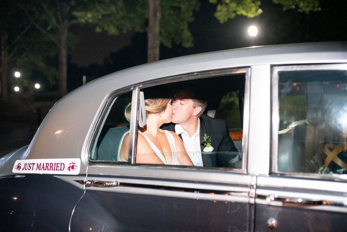 bride and groom kissing in getaway car