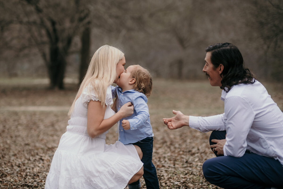 Boy kisses his mother with dad besides.