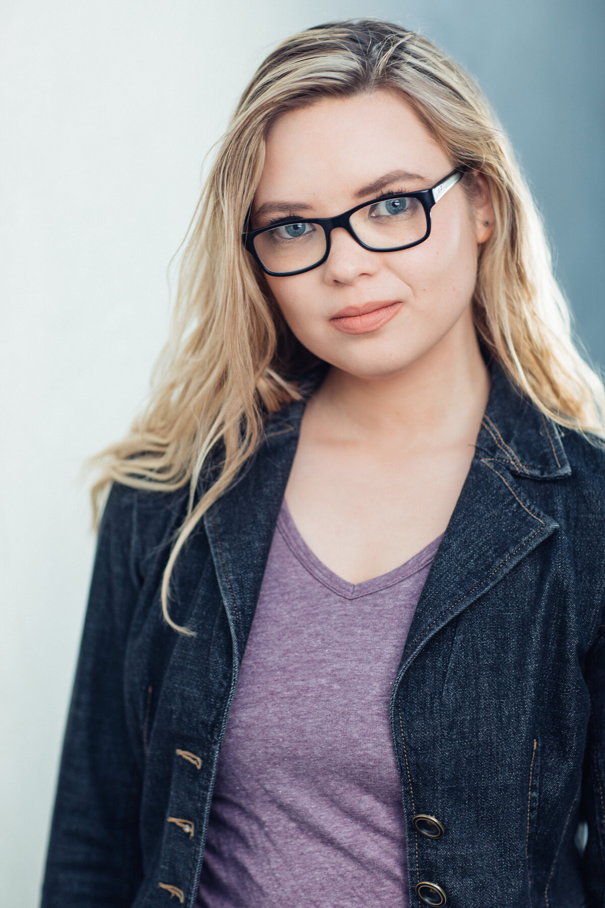 Headshot Photograph Of Young Woman In Outer Black Jacket And Inner Violet V-Neck Shirt Los Angeles