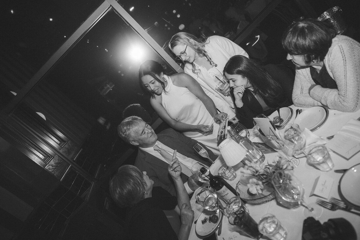 Two brides and their family gathered around a table in a restaurant
