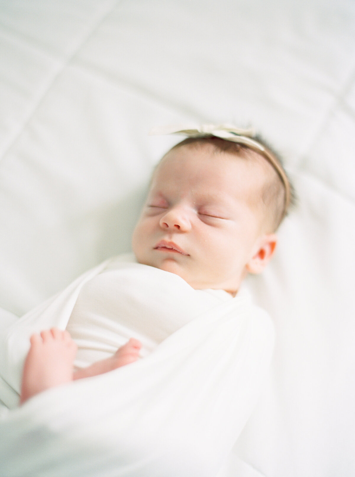 newborn baby girl in all white taken by newborn photography talia laird photography