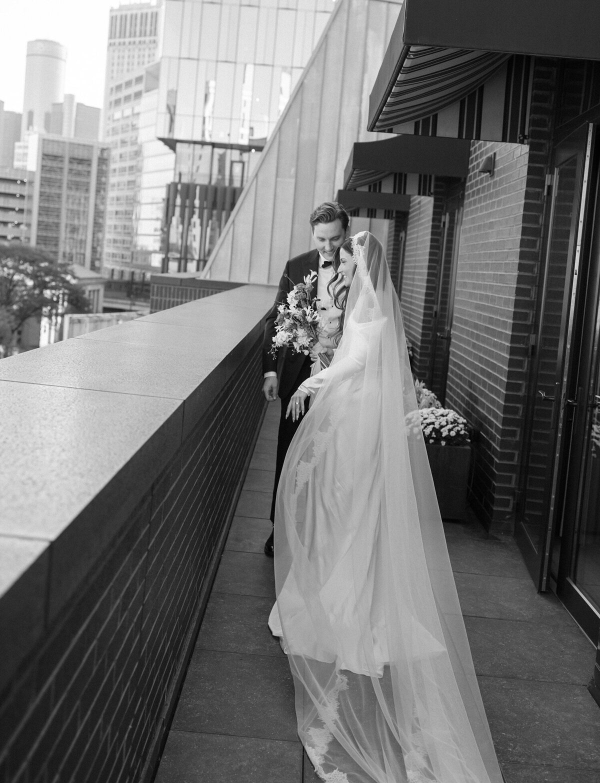 wedding couple first look at Shinola Hotel on balcony, bride with long lace veil