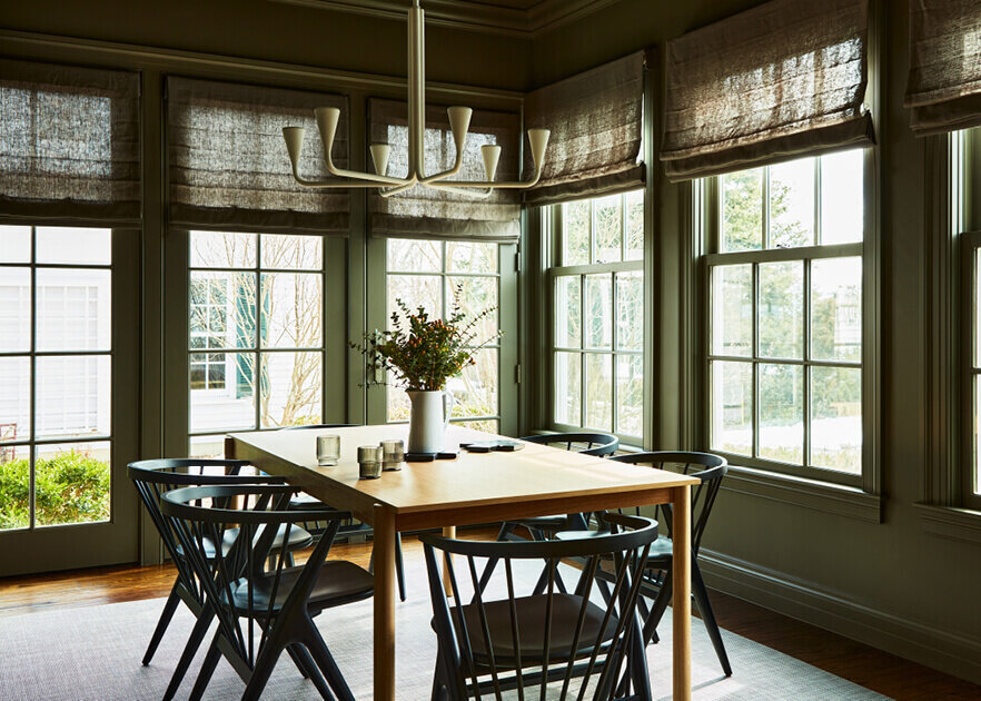 Boston designers create a modern dining room with dark walls and Danish-inspired furniture, blending bold contrast with elegant, minimalist style.