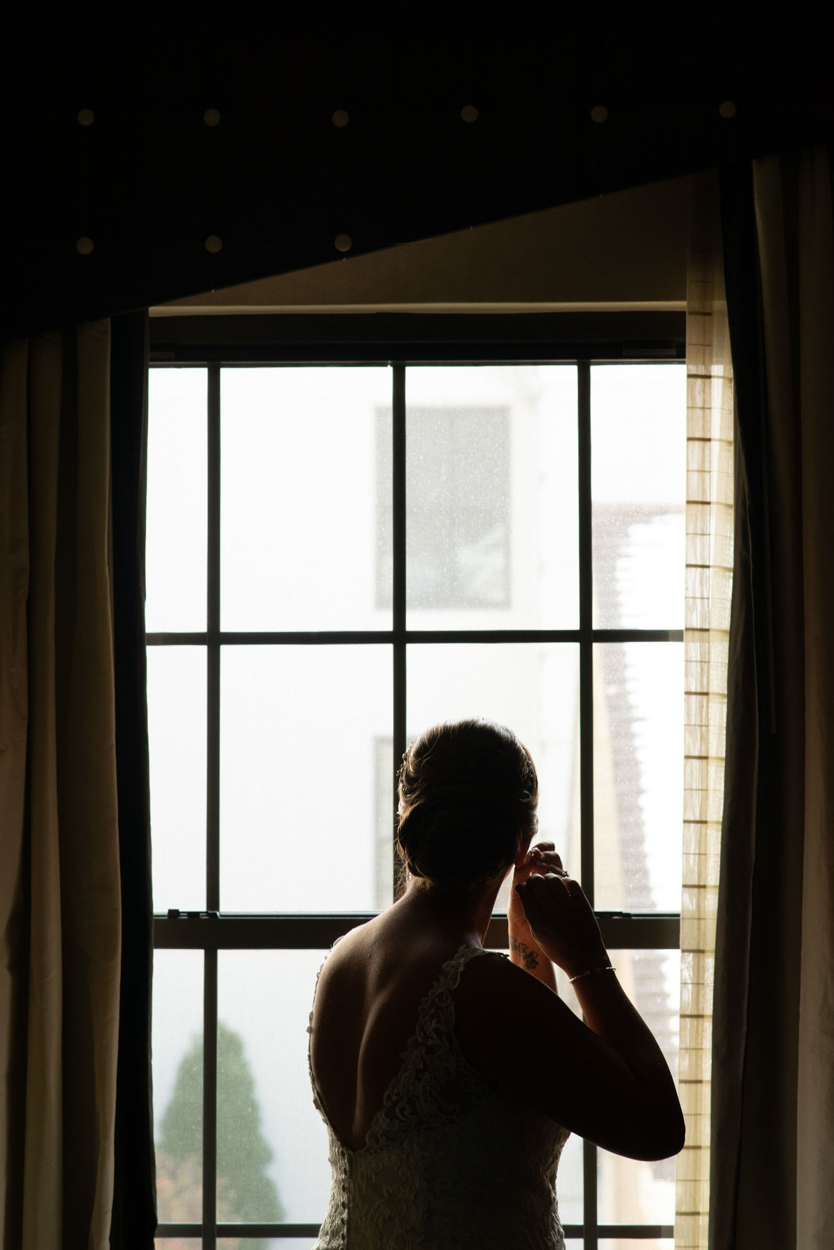 Bride putting in earrings looking out the window at The Inn at Fox Hollow