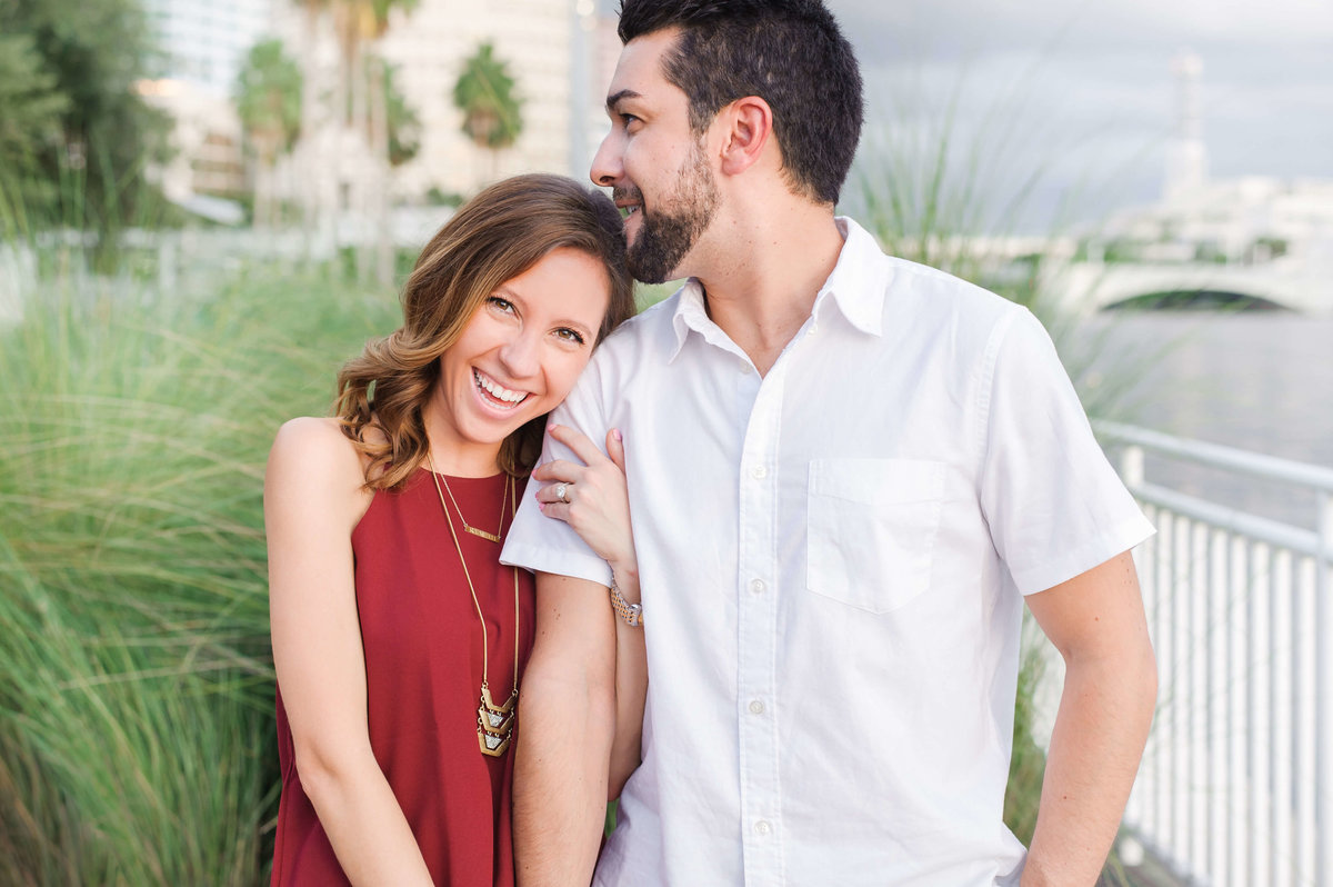 A couple cuddle up along the downtown Tampa riverwalk during their engagement session with Sarah and Ben