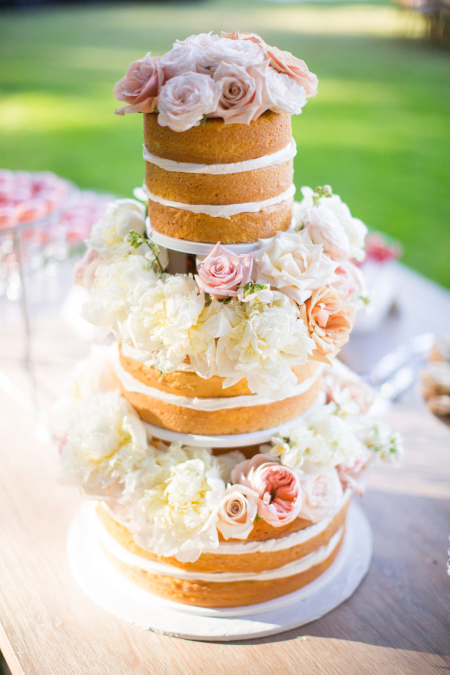 unfrosted wedding cake with flowers in between tiers