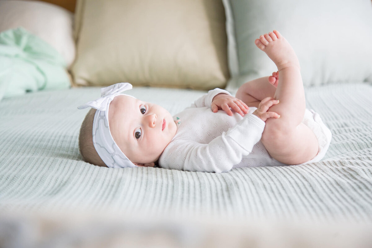 infant baby girl in white ona green bed