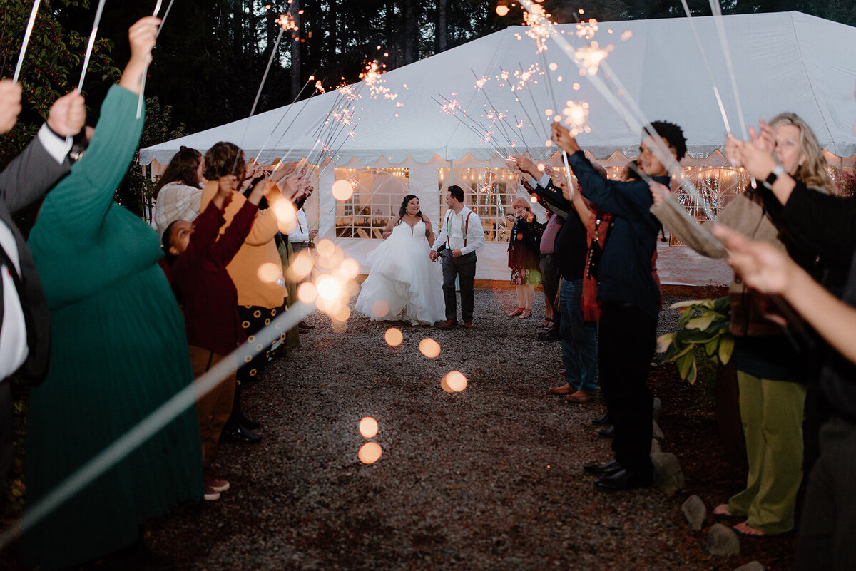 Ashley at her wedding walking down a tunnel of sparklers.