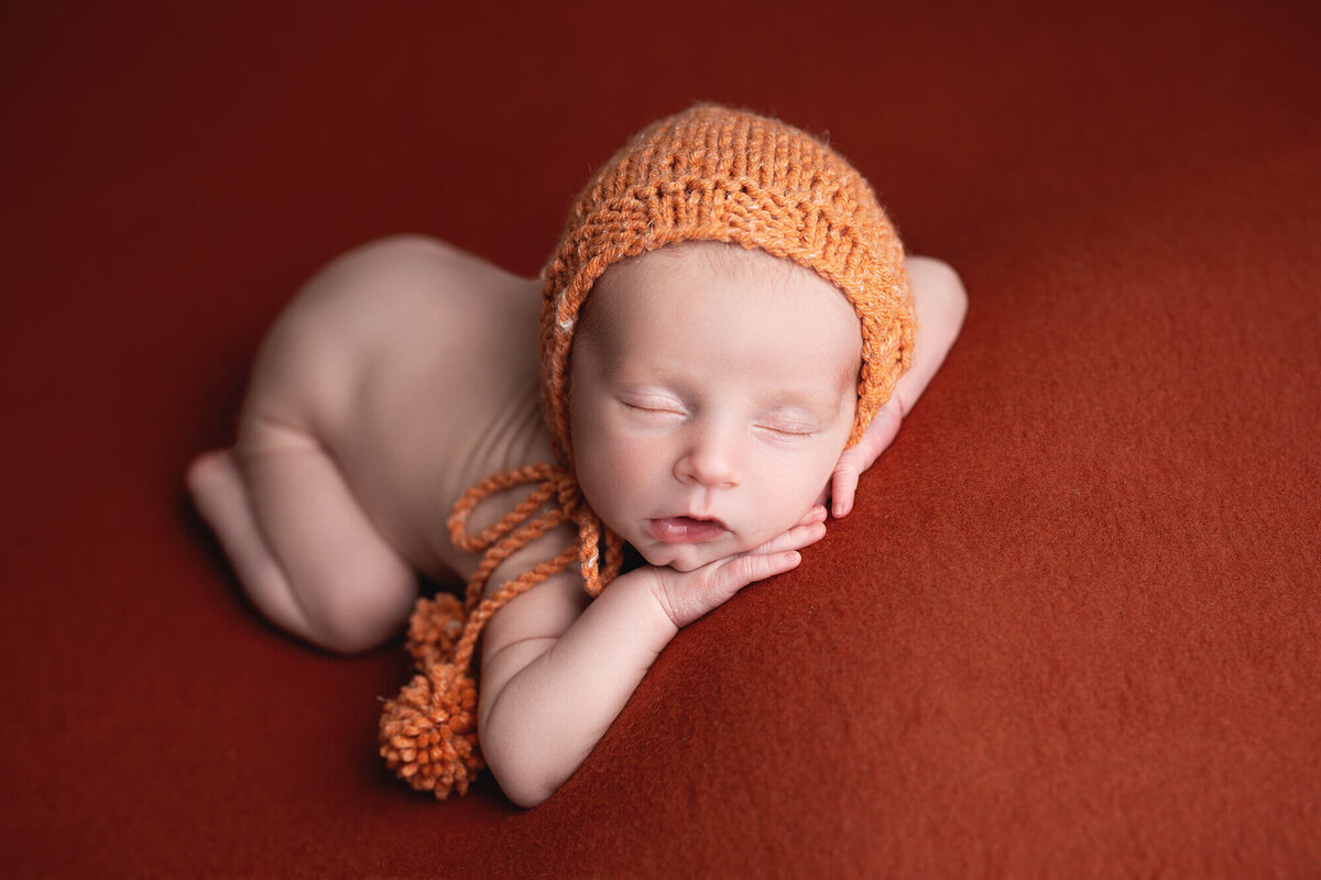 Posed newborn with a fall colored bonnet during his baby photo session at Jennifer Brandes Photography.