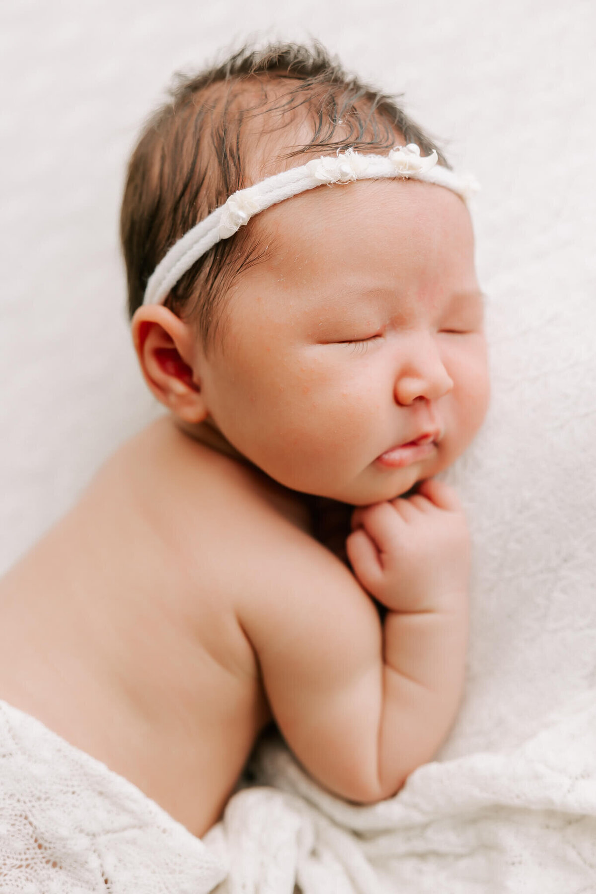 beautiful portrait of infant on her tummy sleeping with her hand under chin