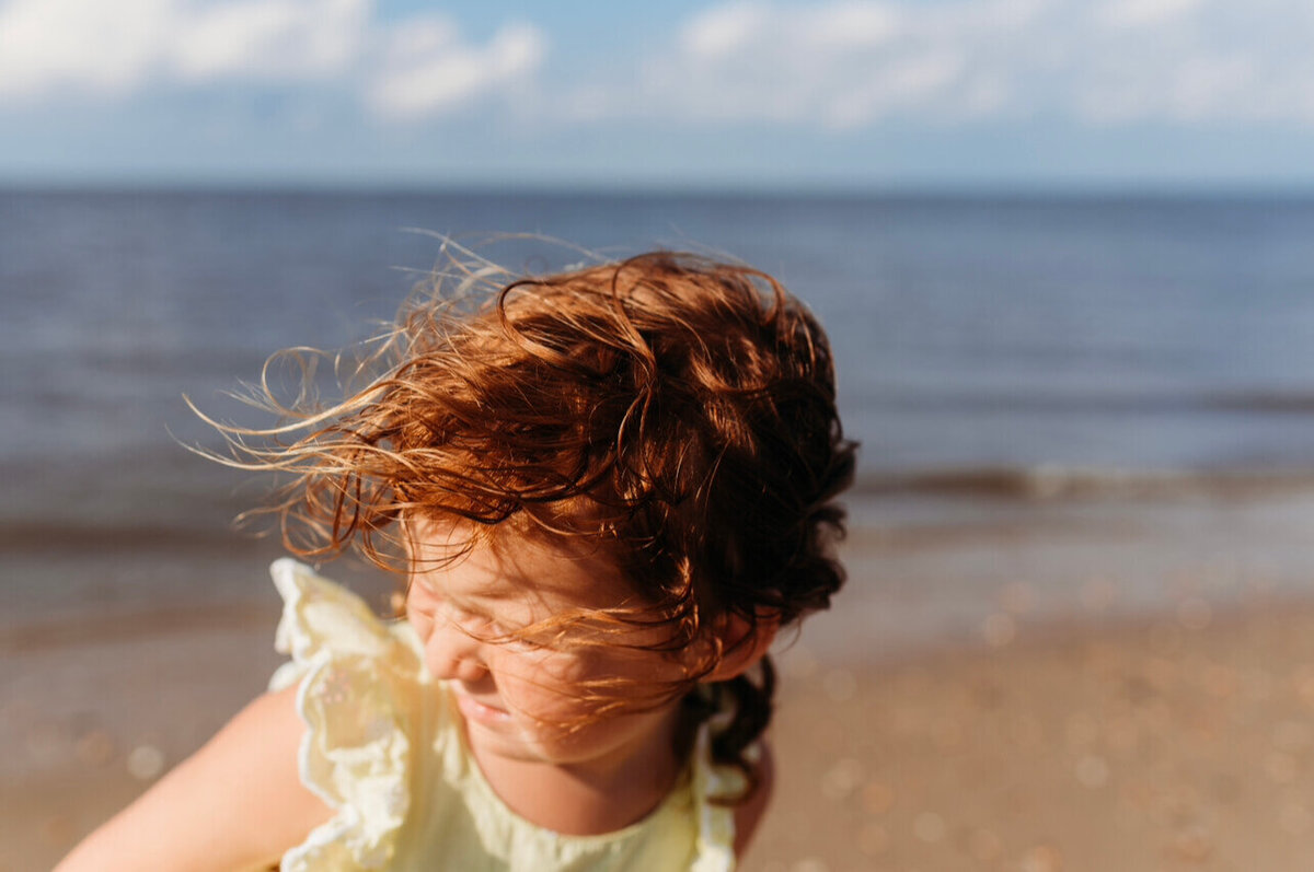 young child with windblown hair on a beach in delaware.  photo taken by Cape May Photographer, Kristi