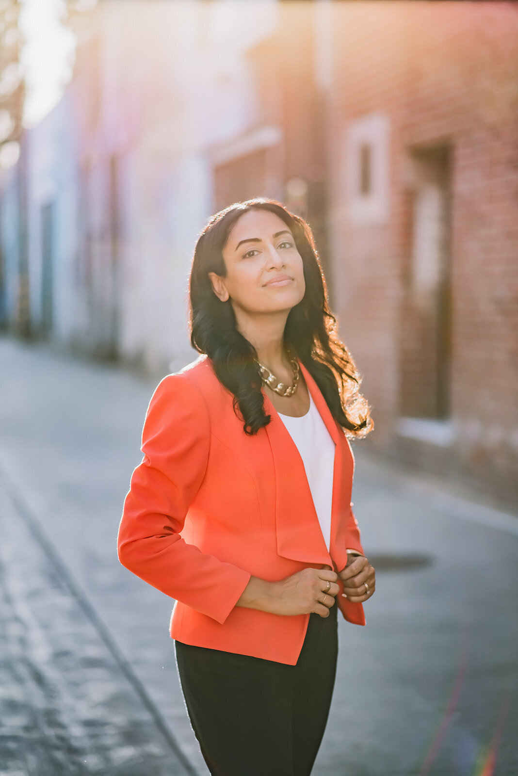 A woman in an orange blazer looks into the camera for headshots in Los Angeles.