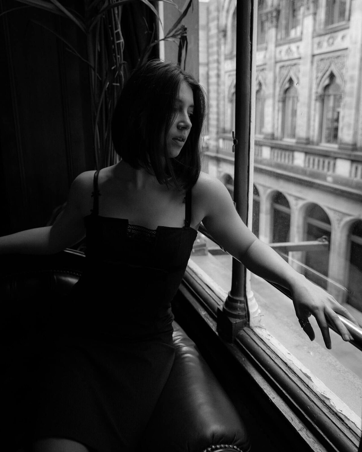 A lady in a slip stares out of the window