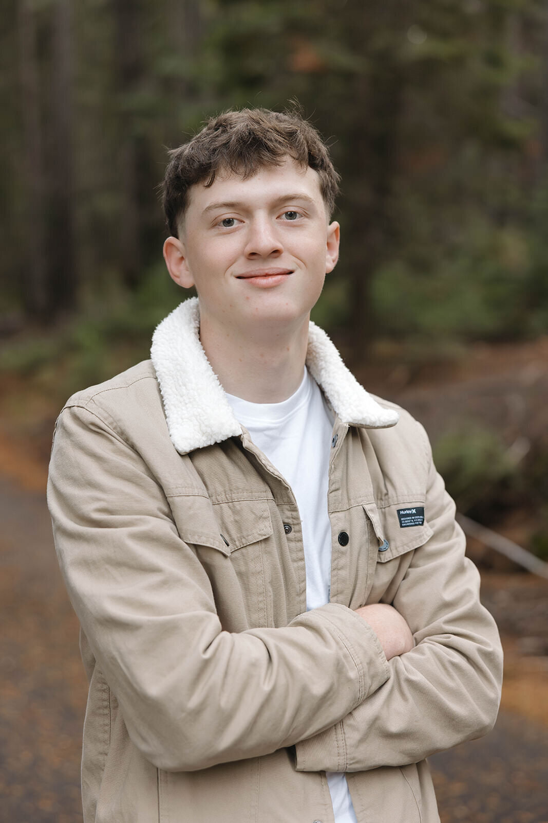 Senior guy smiling with arms crossed on a forest road