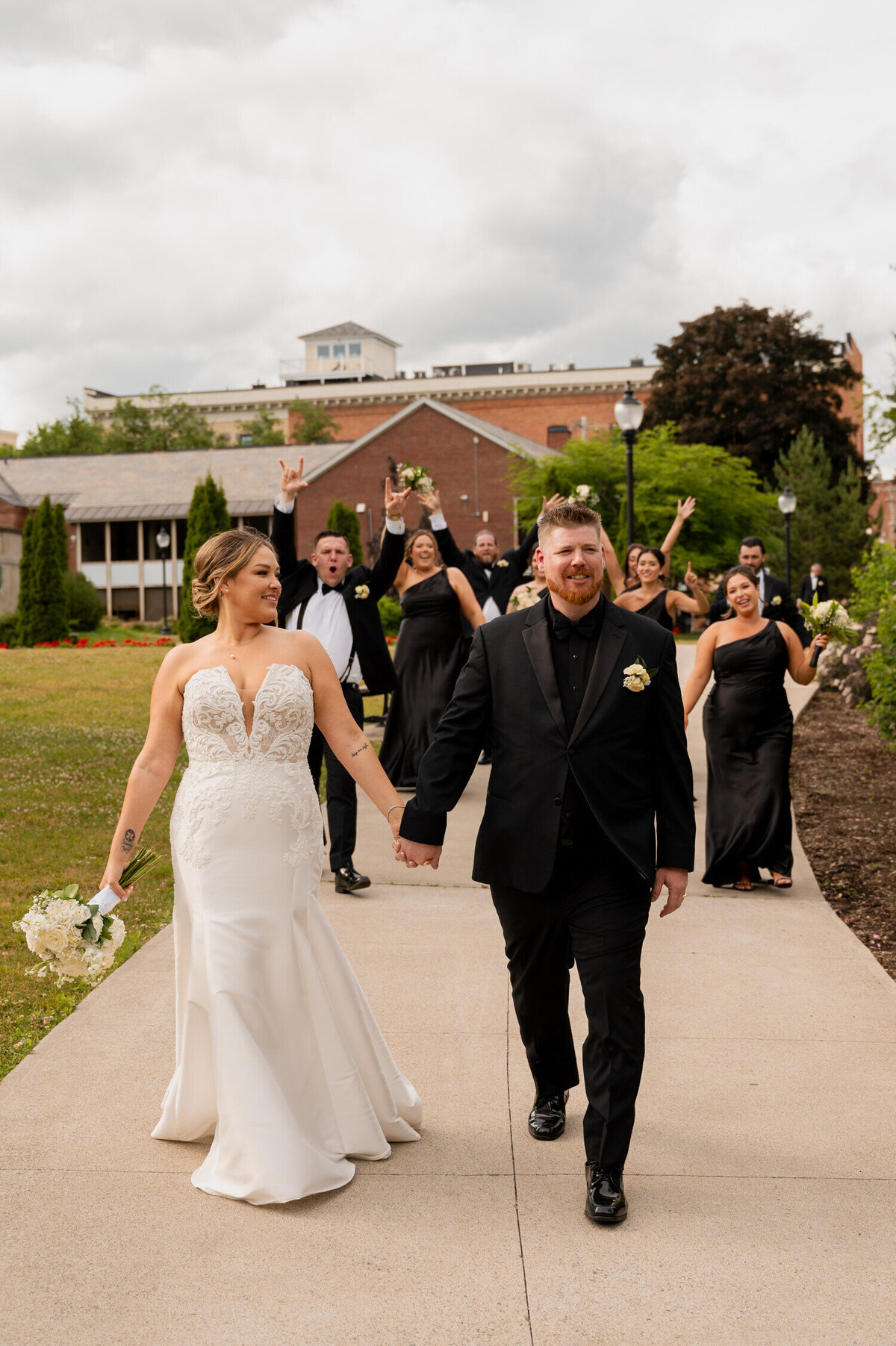 The bride and groom leading their bridal party through Congress Park during a wedding at the Canfield Casino in Saratoga Springs, New York.