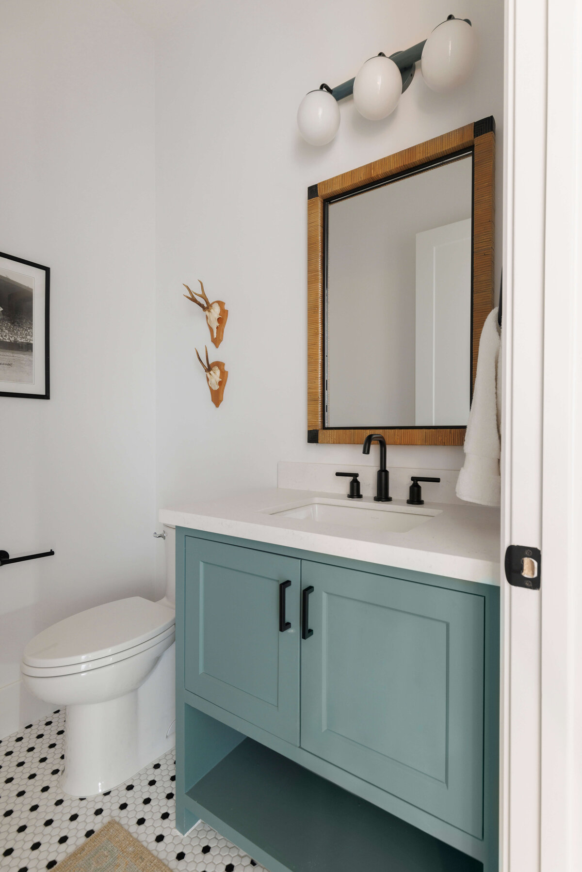 oyster creek studios missouri city new build light blue vanity with white counters black hardware and wooden mirror in bathroom