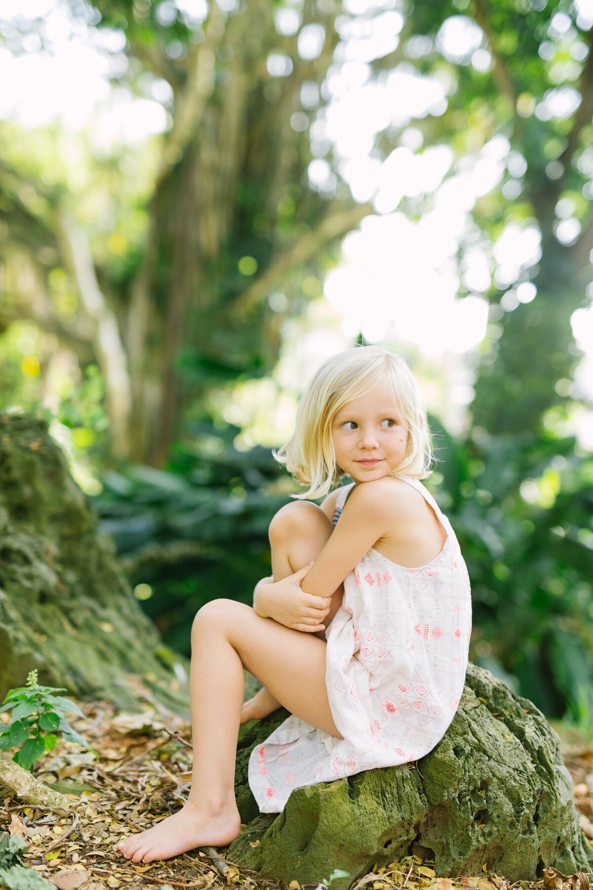 portrait of a young girl sitting on a rock in nuuanu valley park