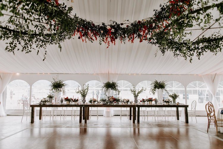 Seating in an event tent with garlands and custom floral arrangements