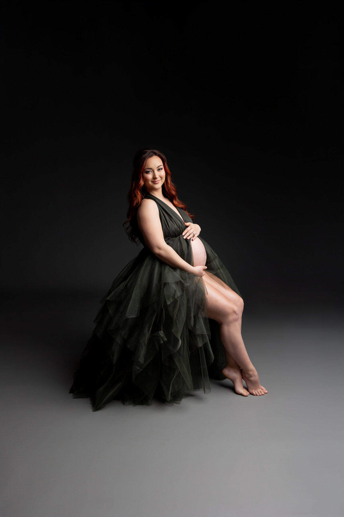 Wearing a black dress, she strikes a side pose, her serene expression captured in soft, flattering light. Captured by Inland Empire photographer Kaitlyn Dawn Photography.