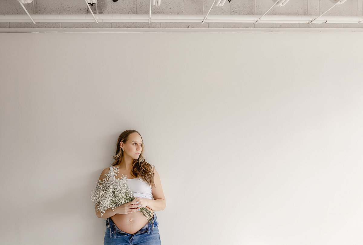 modern denver studio with light with a oregnant mom holding flowers