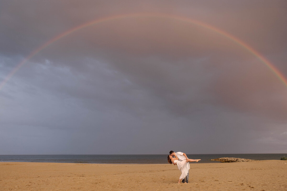 A couple kissing on the beach at Sandbanks under a rainbow