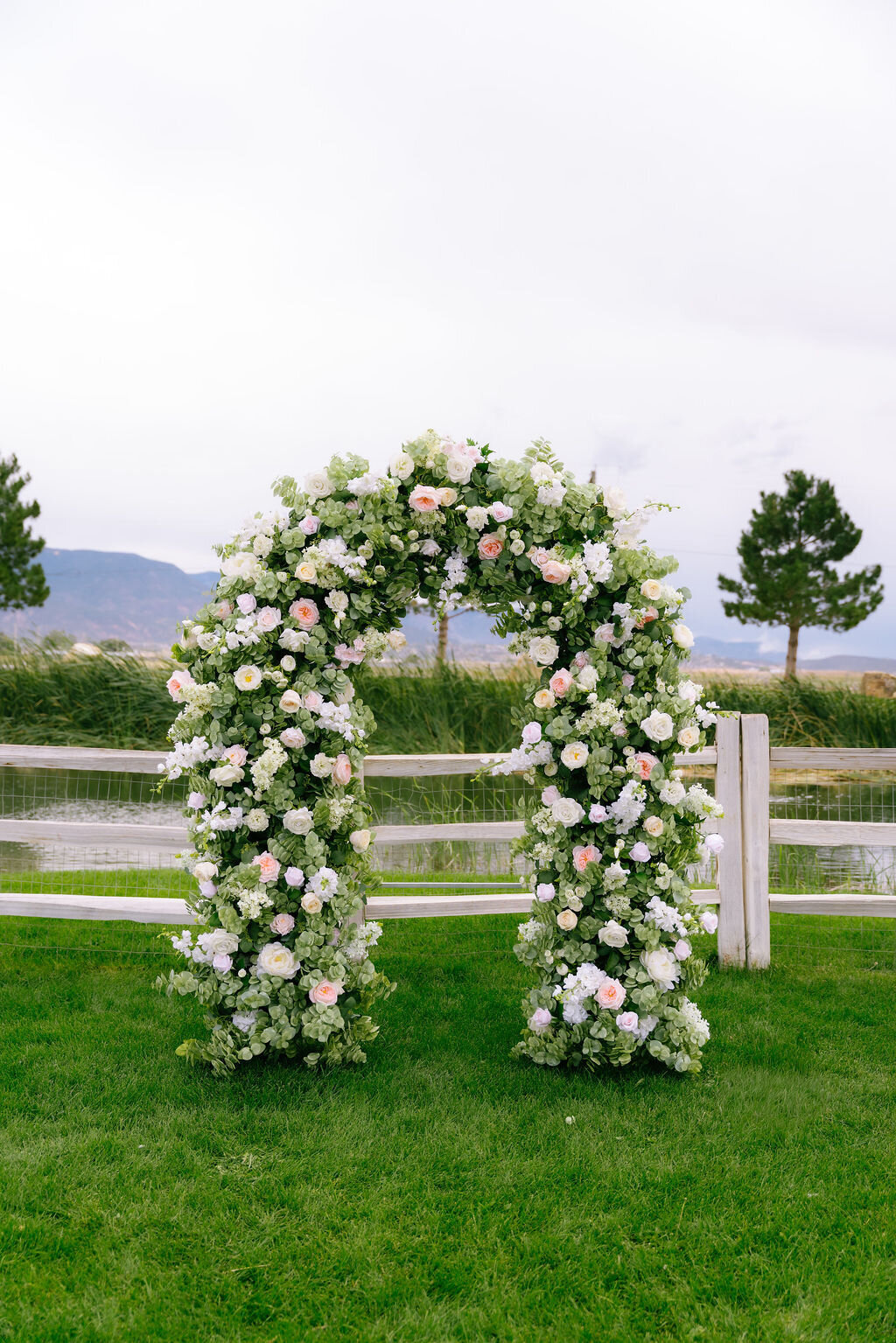 Floral ceremony arch on the lawn with mountains behind