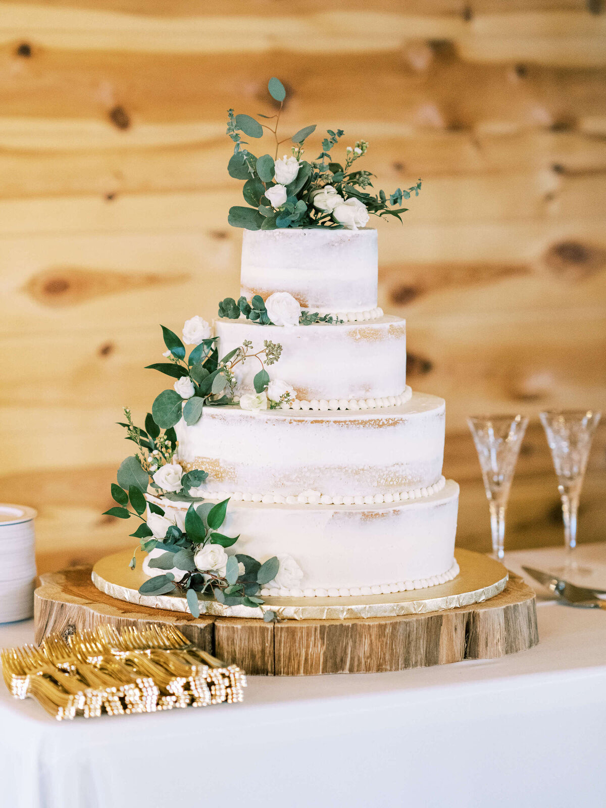 Elegant rustic naked cake with light greenery and white roses