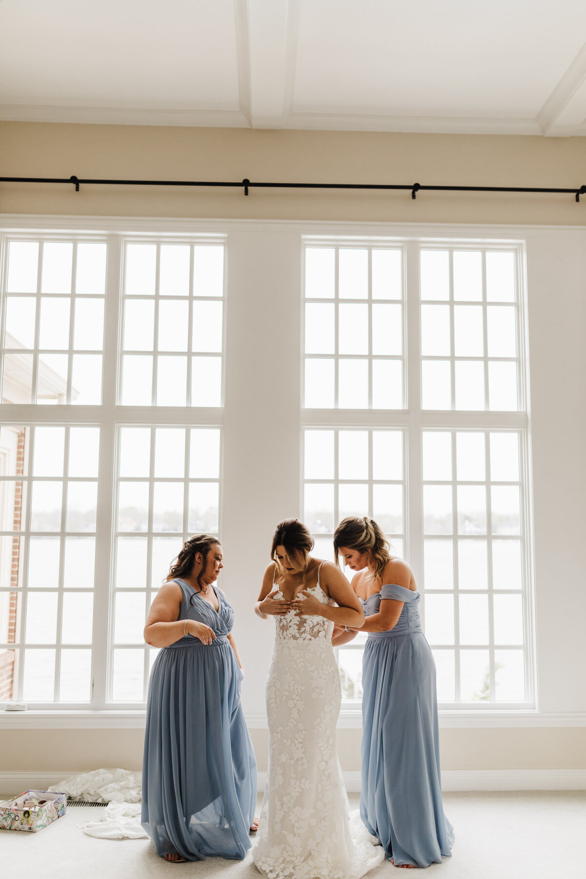 Bride getting help into her dress by bridesmaids
