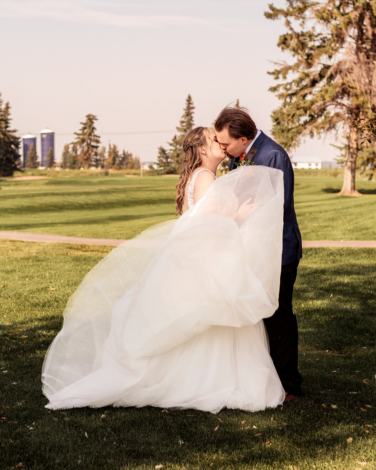 Brides dress tossed up as she kisses her groom