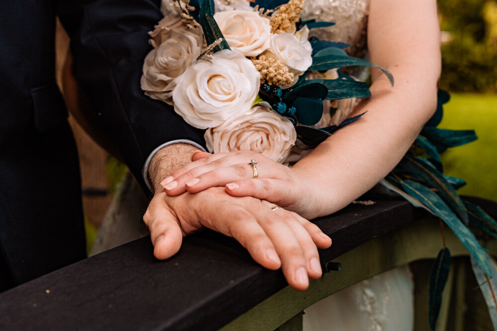 bride and groom holding hands on a bridge and showing off wedding rings - Townsville Wedding Photography by Jamie Simmons