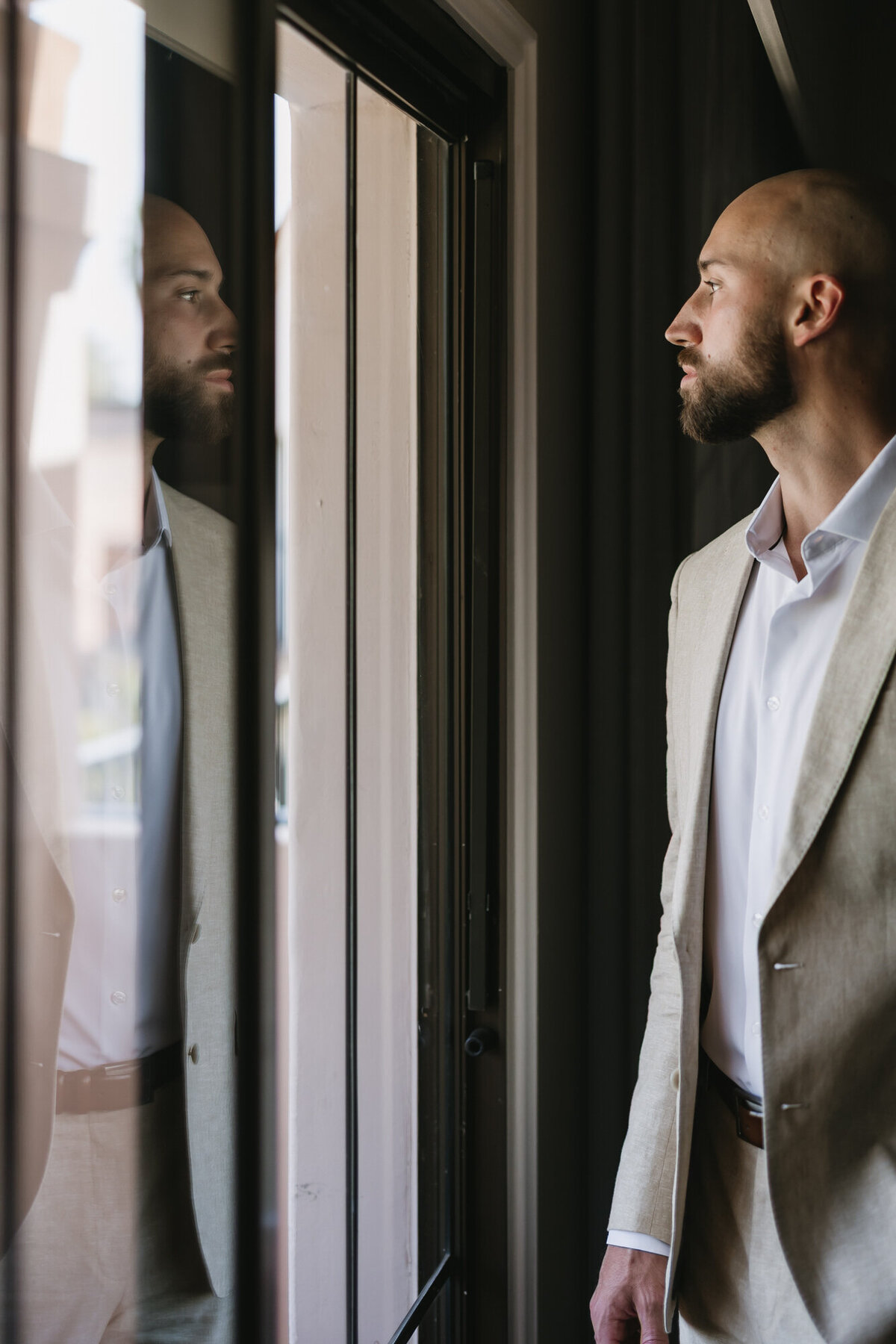 Groom looking out of window while getting ready for wedding day at Hilton Beachfront Resort Santa Barbara