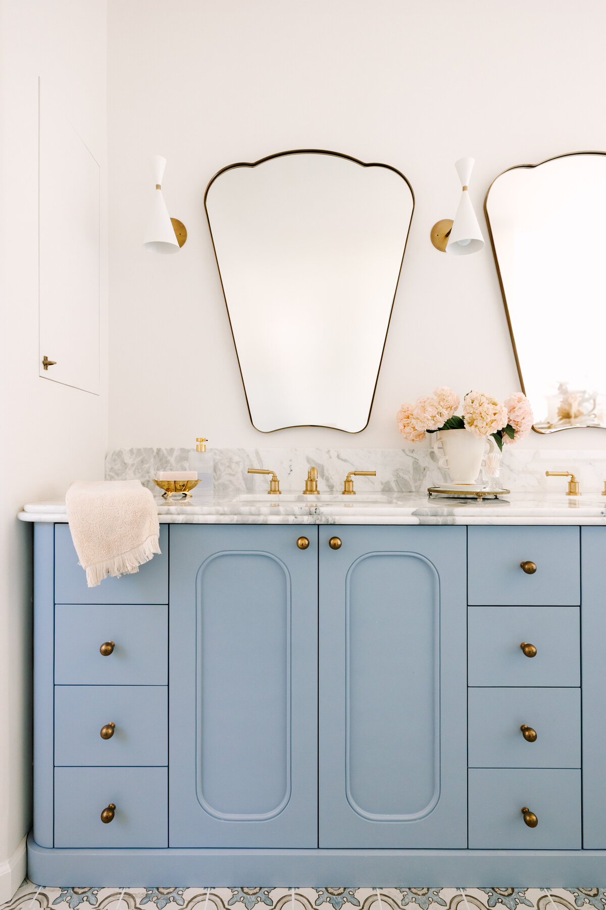 Primary bathroom with a custom vanity in Sherwin Williams Lakeside and rounded edges, Arabescato Corchia marble counters, Italian shield mirrors, Blueprint Lighting Monolith Wall Sconce, and hidden medicine cabinet. 
