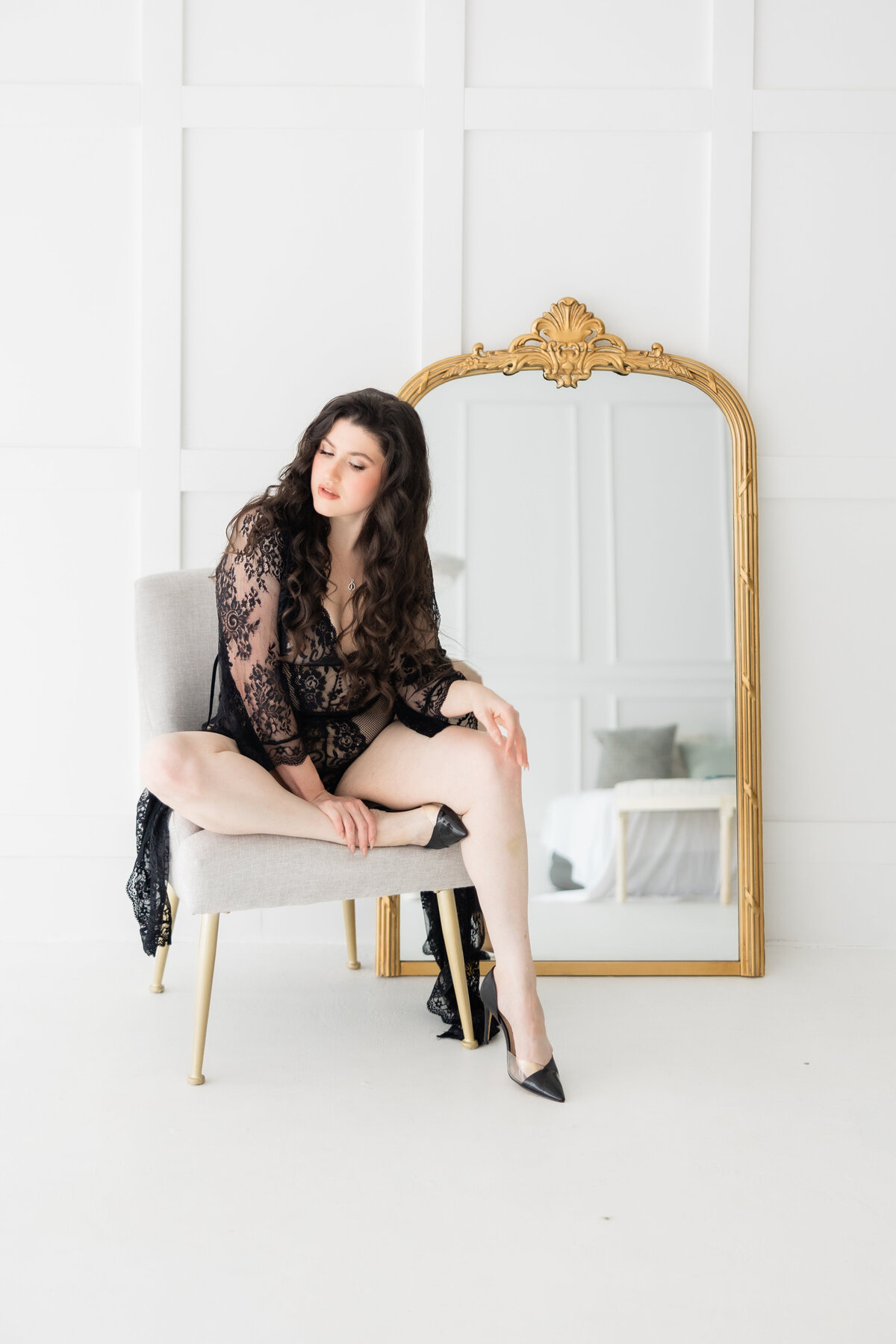 A woman sitting in a chair in black lace in a boudoir photo at the Brand studio orlando 
