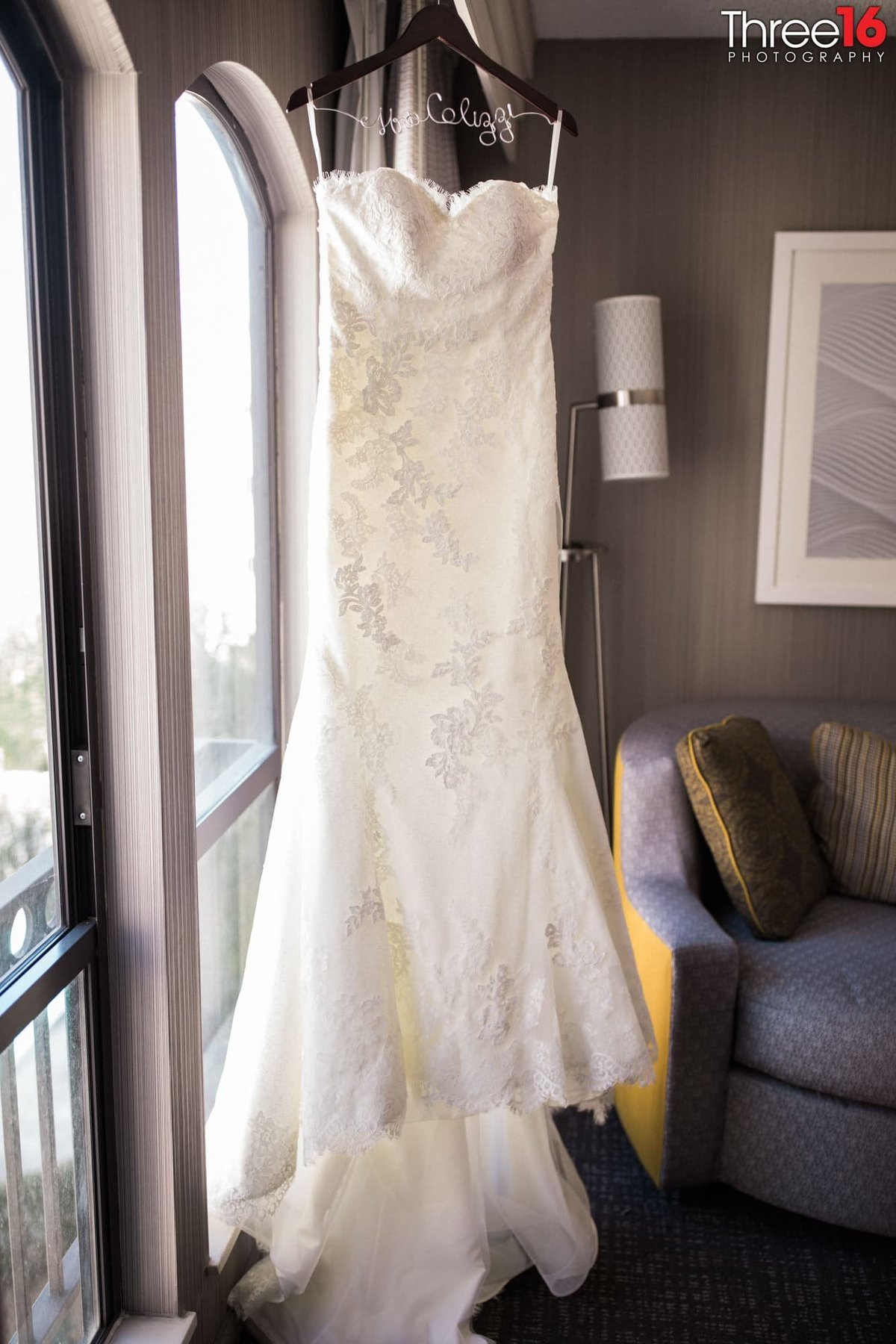 The Brides wedding gown hanging in front a window