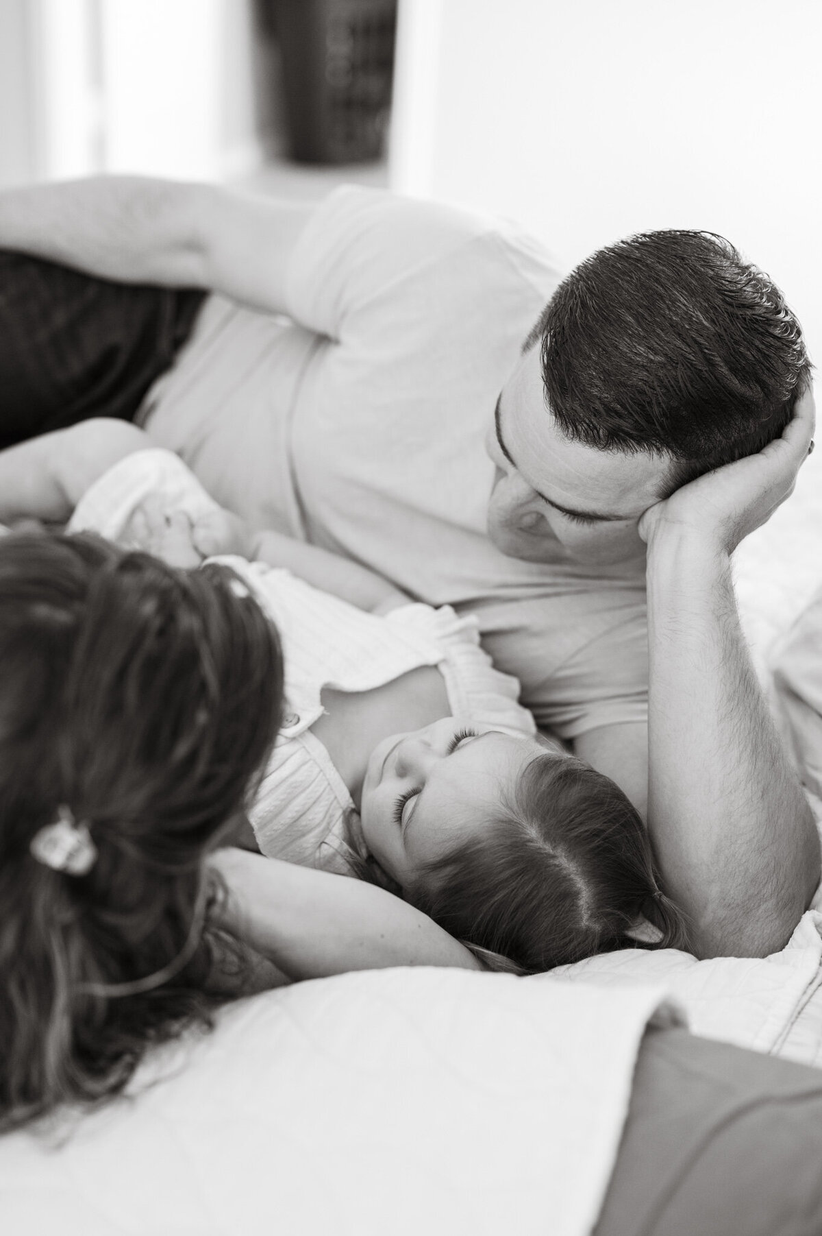 Black and white image of a dad gazing down at his daughter during lifestyle newborn pictures in San Antonio.