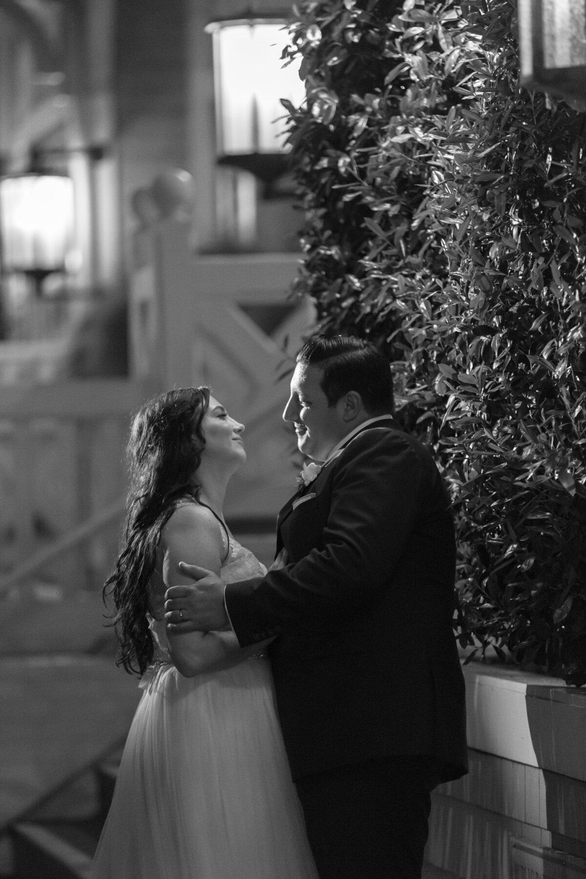 A bride and groom with their arms around each other smiling